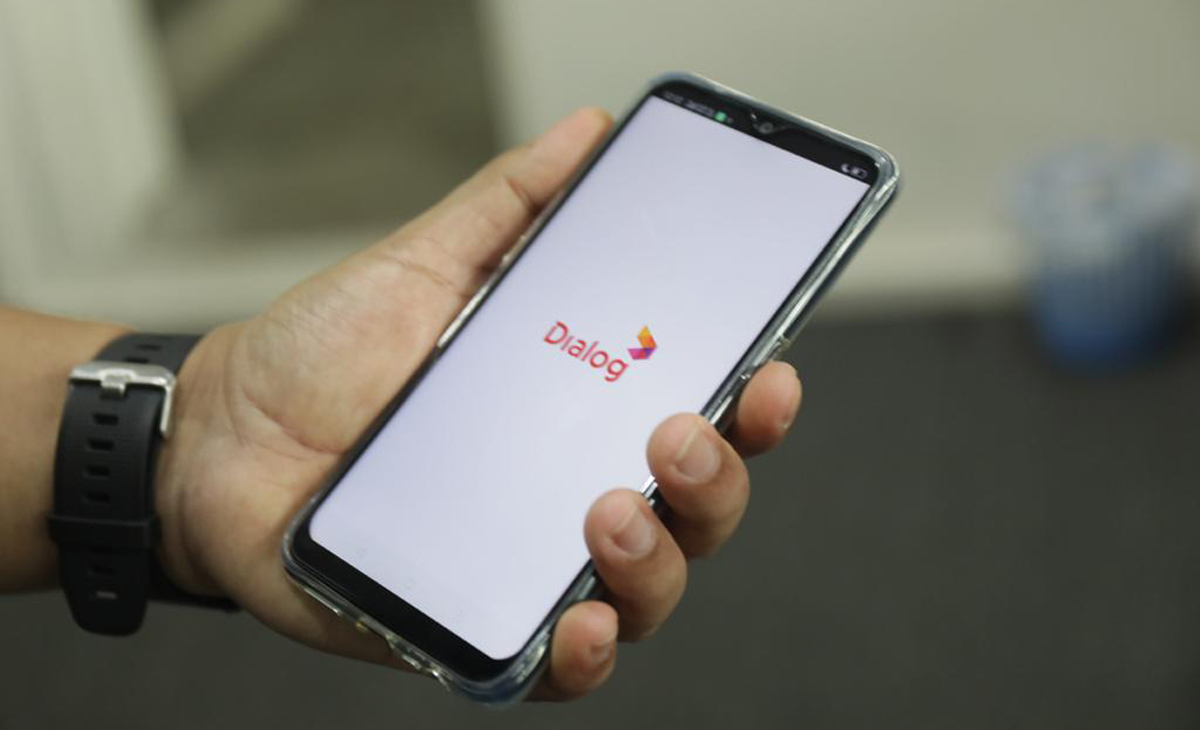 A close-up of a hand holding a smartphone displaying the Dialog Axiata splash screen, symbolizing mobile connectivity and brand presence in Sri Lanka's telecommunications sector.